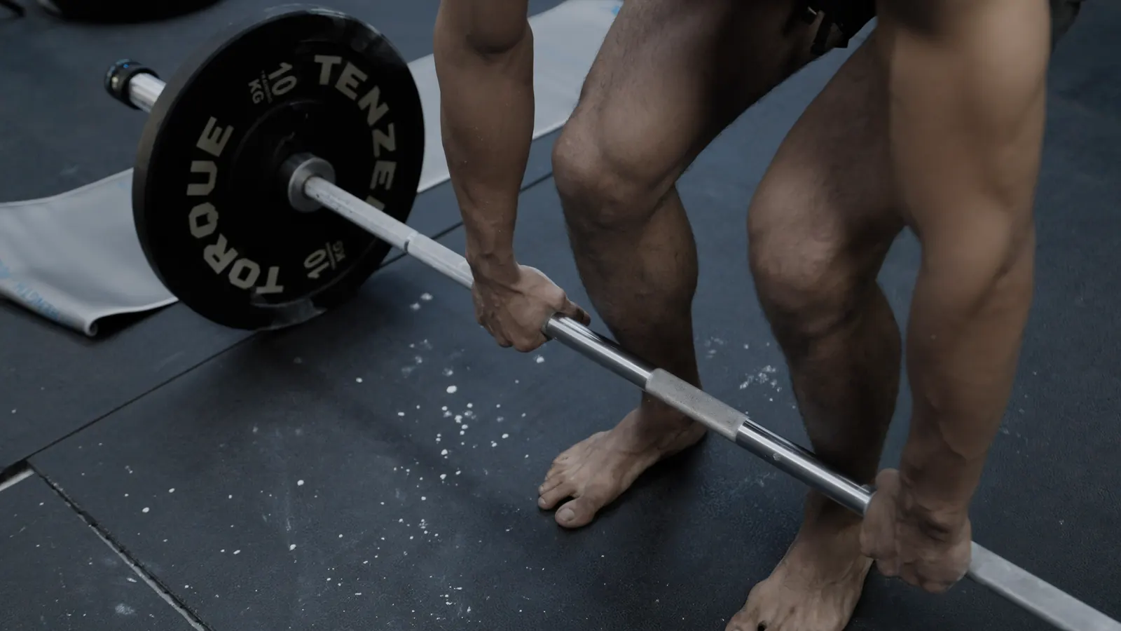 Athlete gripping a loaded barbell at the start of a deadlift
