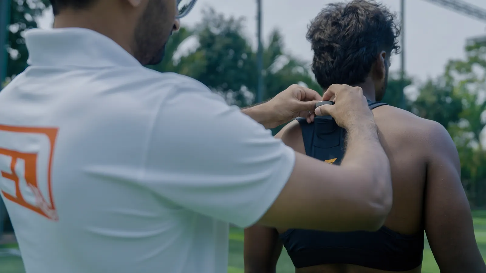 EvoQuest coach fitting a GPS vest on an athlete on the training pitch