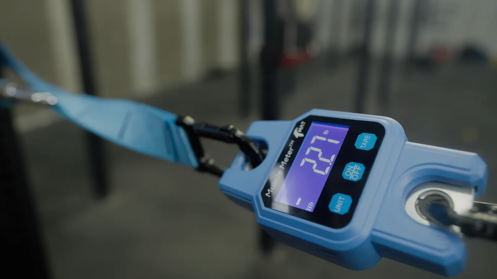 Handheld muscle-strength meter under tension on a strap